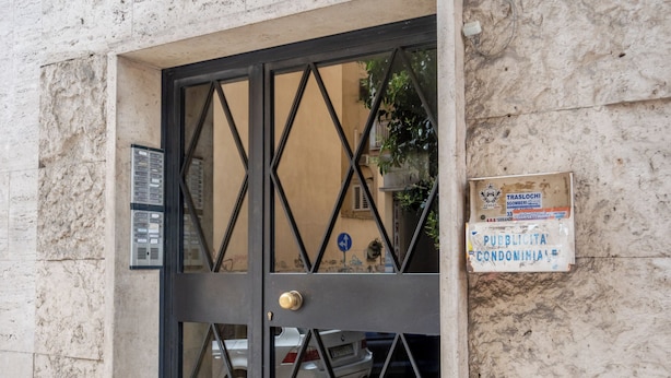 A building entrance with a numbered door, a sign indicating public housing, and a visible staircase.