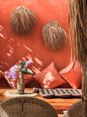 Un intérieur rustique agrémenté de paniers tressés, d’un vase tressé contenant des fleurs et d’un tapis tressé posé sur une table en bois.