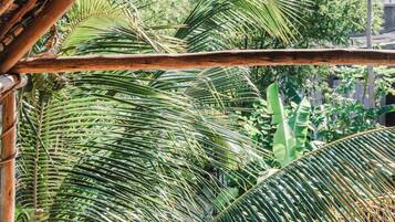 A hammock under a bamboo structure with a view of palm trees.