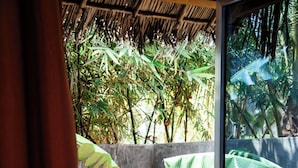 A room with a concrete wall, a bench with cushions, a small round table, and a bottle. - Green Ocean Zanzibar Boutique Hotel (Jambiani)