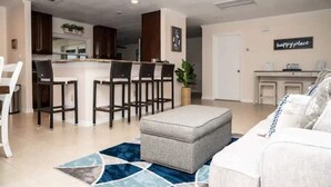 A modern living room with a grey ottoman, a white sofa, and a blue patterned rug. - Tranquil Lakefront Retreat (Lake Placid)
