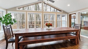 A dining room with a large wooden table, chairs, and a ceiling fan.
