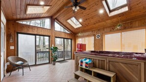 A wooden interior with a large window, a ceiling fan, and a wooden bench.