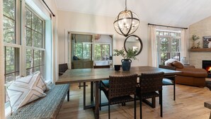 A spacious living room with a large wooden dining table, comfortable seating, and a fireplace. - Lakeside Getaway Theatre, Indoor Pool and Game Room (Gouldsboro)