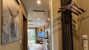 A hallway with wooden flooring, a mounted deer painting, a coat rack, and a television in the background. - Gemütliches 4 Ferienhaus mit Whirlpool, Fitness, Infrarotsauna, Ebike, Alpakas (Braunfels)