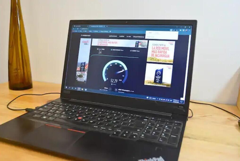 Ein Laptop auf einer Holztischplatte, auf dem ein Webbrowser geöffnet ist und ein Geschwindigkeitstest angezeigt wird.
