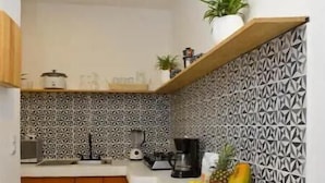 A compact kitchen with a central island, wooden cabinets, a patterned backsplash, and a fruit bowl on the counter.