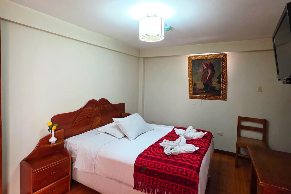 Un dormitorio ordenado con cama, mesita de noche y escritorio.