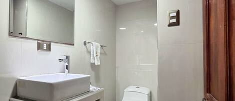 A bathroom with a white sink, mirror, and toilet.