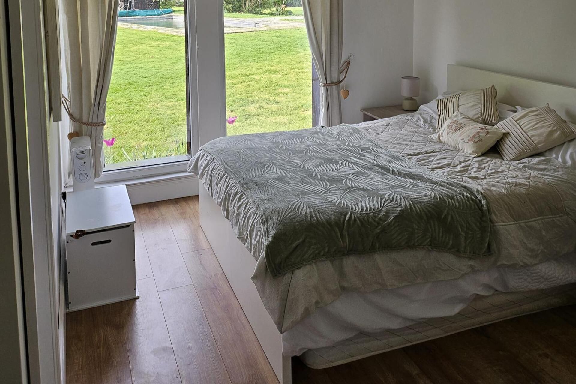Quarto com cama, cortinas, mesa de cabeceira e abajur.