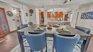 Un comedor con una mesa grande, sillas tapizadas en azul y un ventilador de techo.