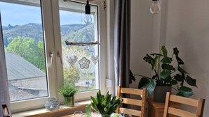 Ein Esstisch, gedeckt für sechs Personen, mit Blick auf eine Berglandschaft durch große Fenster.