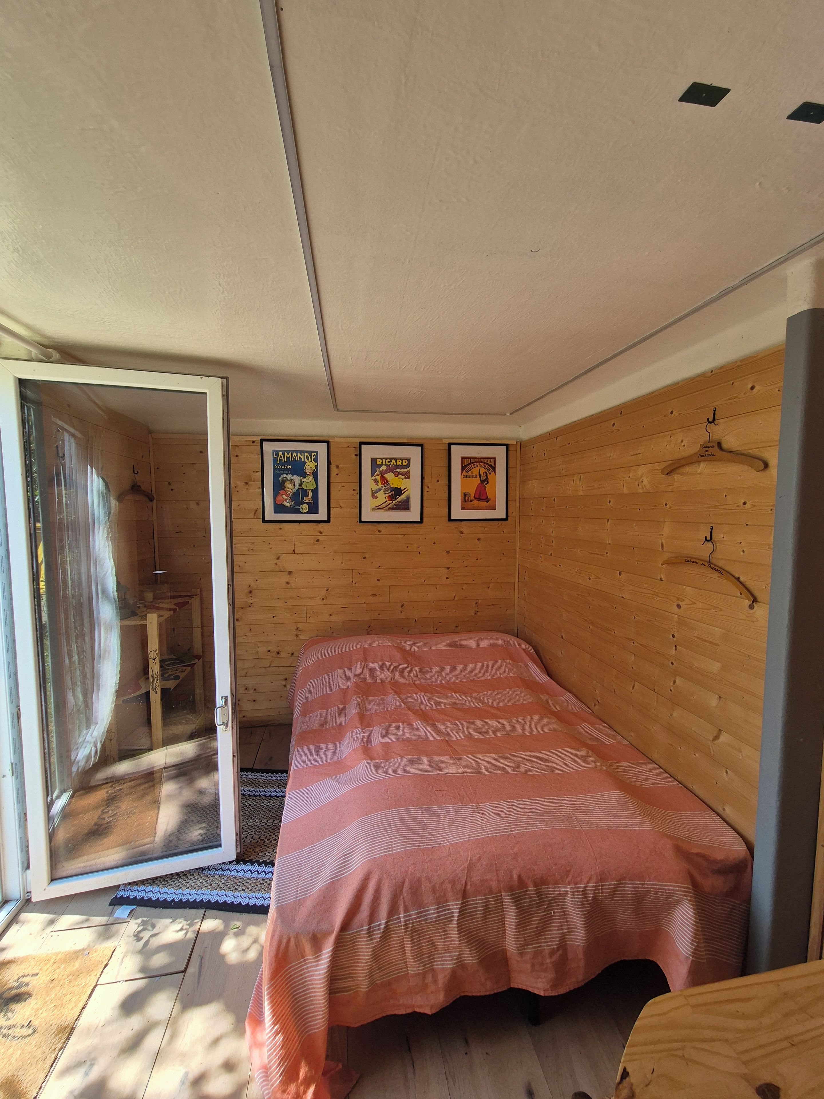 Ein Zimmer mit einem Bett, Holzwänden und einer Tür zu einem Badezimmer.