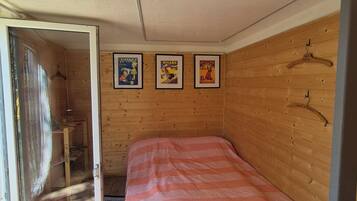 Ein Zimmer mit einem Bett, Holzwänden und einer Tür zu einem Badezimmer.