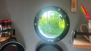 Eine Küche mit rundem Fenster, einer schwarzen Bratpfanne und einem Holzboden.