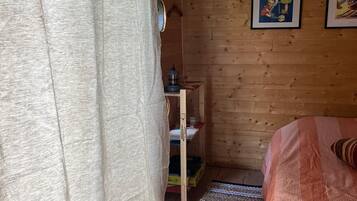 Une pièce avec un lit, une étagère en bois, un rideau et une affiche accrochée au mur.