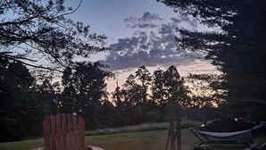 A fire pit with logs, a wooden Adirondack chair, and a hammock in a garden setting. - POND IN THE PINES CABIN -COMPLETELY RENOVATED ON 27 ACRES - POND-HOCKING HILLS (McArthur)