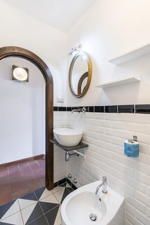Bathroom features a white sink, chrome faucet, round mirror, and black and white geometric tile floor.