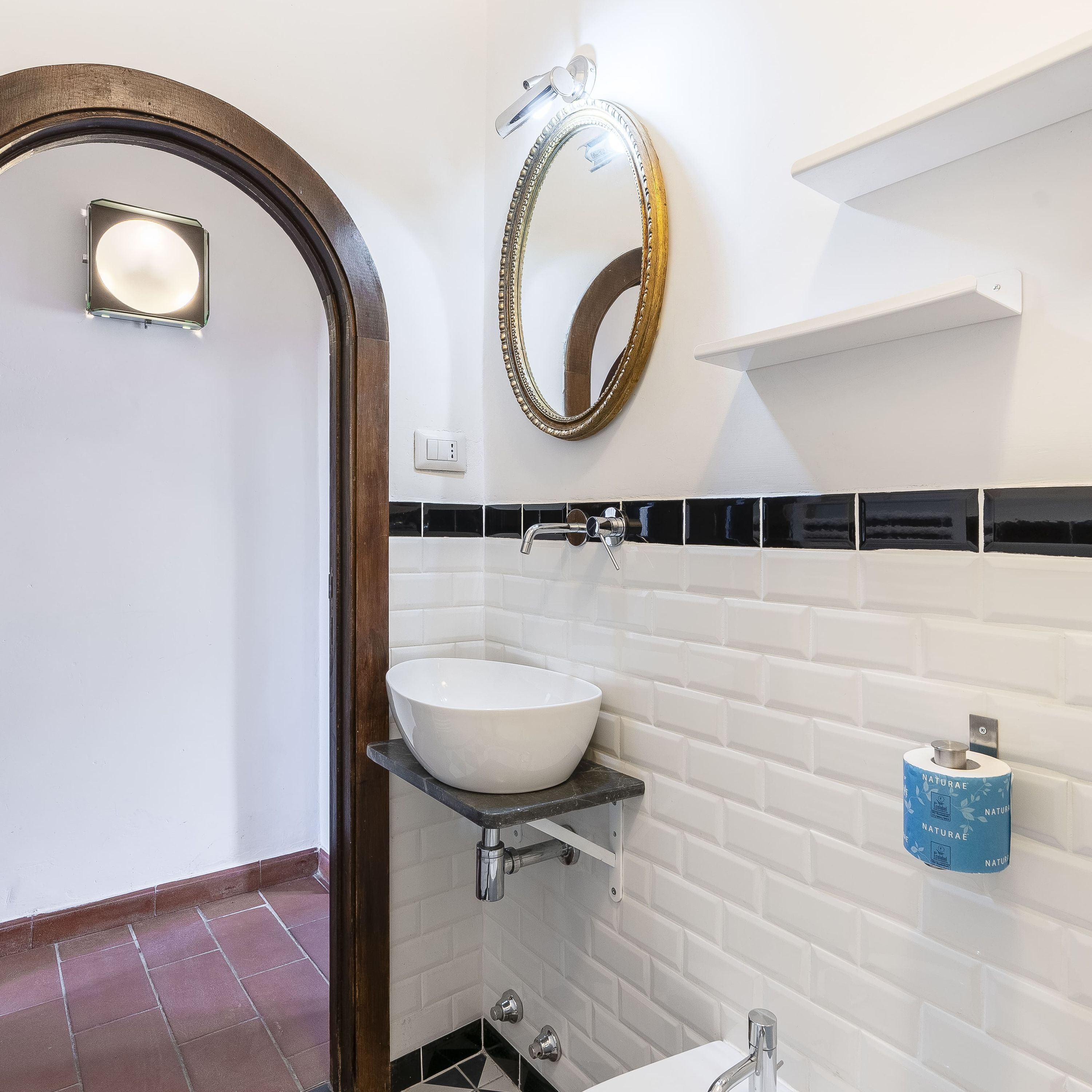 A bathroom with a white sink, a mirror, and a toilet paper holder.