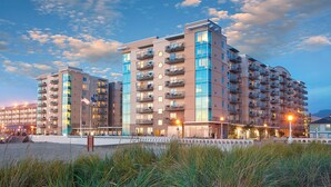 A multi-story hotel with balconies, located near a beach with a fence and grassy area in the foreground. - Worldmark Seaside, Beachfront Resort!! Add Nights 5, 6 &7 only 50 each. (Seaside)