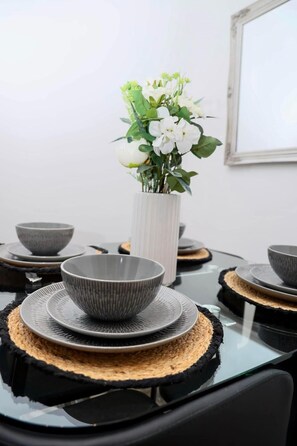 A dining table with grey bowls and a white vase with flowers. - Immaculate 3-bed Apartment Homes in London (London)