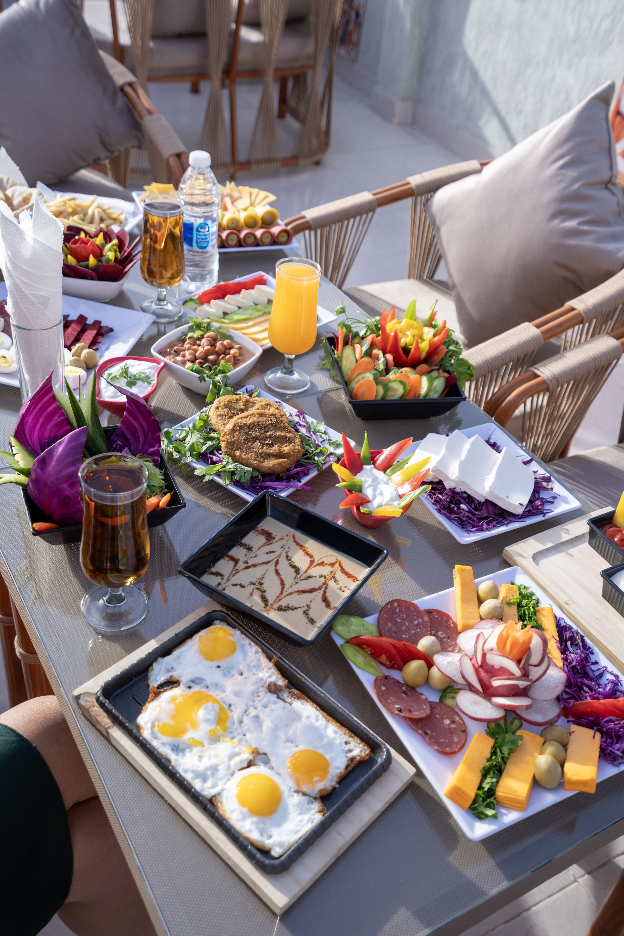 A table set with a variety of breakfast items including eggs, meats, cheeses, fruits, and vegetables.