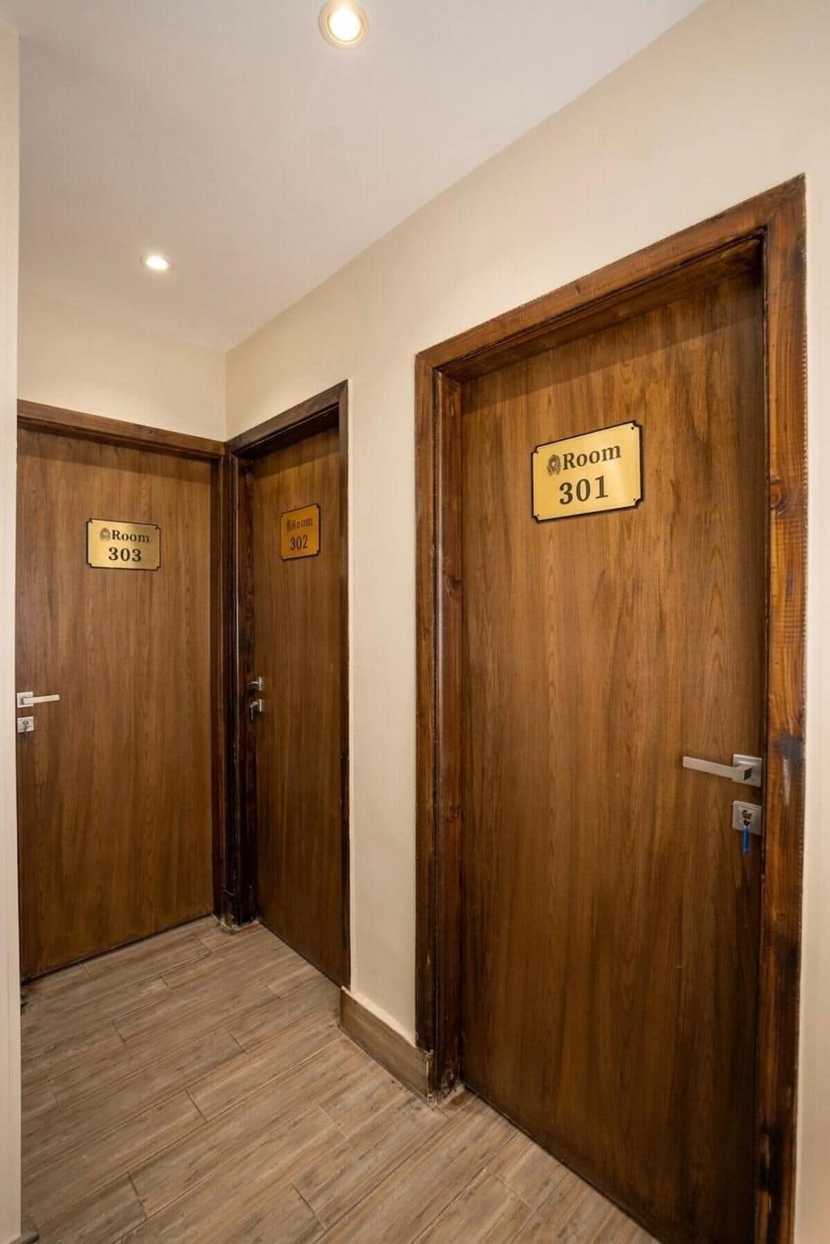 Un pasillo con puertas de madera, cada una identificada con los números de habitación 301, 302 y 303.