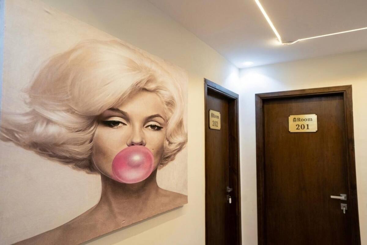 A hallway with a large portrait mural, two doors labeled 'Room 201' and 'Room 202', and a modern light fixture on the ceiling.
