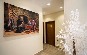 A hallway with a large painting, a wooden door labeled '304', and a white artificial plant. - King of Pharaohs Pyramids View (Giza)