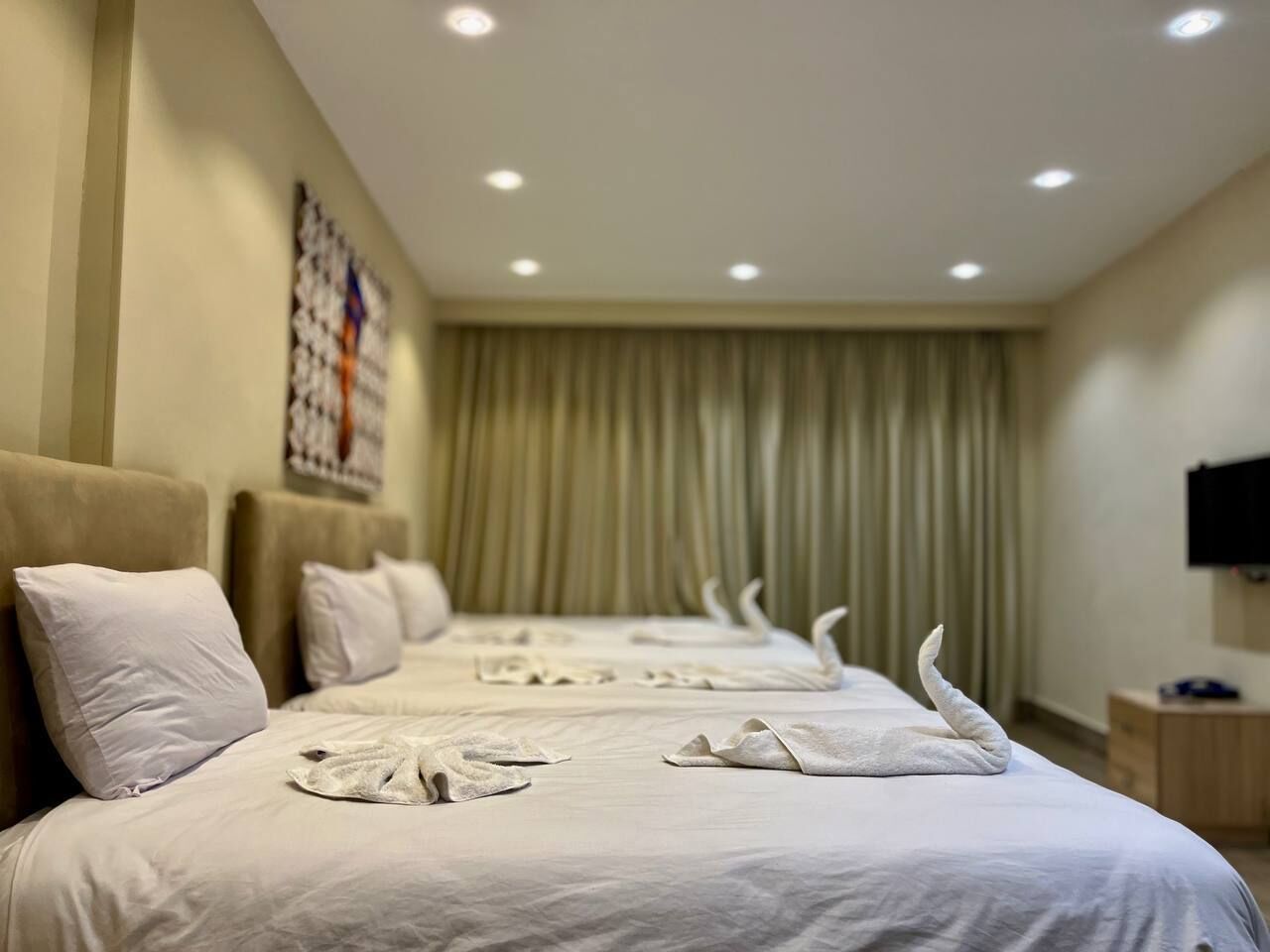 Une chambre d’hôtel avec un grand lit, plusieurs oreillers, un téléviseur à écran plat et un rideau.