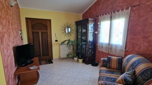 A living room with a sofa, television, cabinet, and potted plants. - Holiday Home Piscinas (SU)
Nice apartment a few kilometers from the sea (Piscinas)