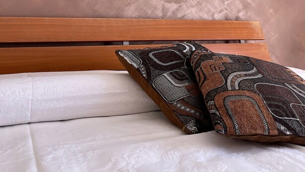 A bedroom with a wooden headboard, a bed with white bedding, and a decorative pillow. - Holiday Home Piscinas (SU)
Nice apartment a few kilometers from the sea (Piscinas)