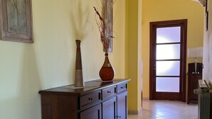 A hallway with a wooden cabinet, a vase with branches, a framed picture, and a door with frosted glass panels. - Holiday Home Piscinas (SU)
Nice apartment a few kilometers from the sea (Piscinas)