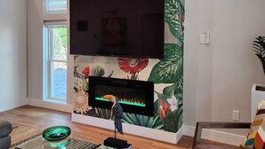 A living room with a large wall mural, a flat-screen TV, and a fireplace. - New, unique custom-built cottage, between Savannah and Tybee Island.  (Savannah)