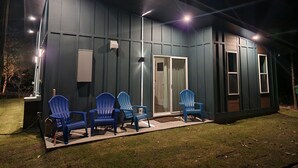 A house with a covered porch, a sliding glass door, and a small outdoor seating area with chairs. - New, unique custom-built cottage, between Savannah and Tybee Island.  (Savannah)