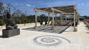 A rooftop garden with a Buddha statue, a geometric patterned floor, and a pergola with hammocks. - Magic jungle apartment in Tulum (Tulum)