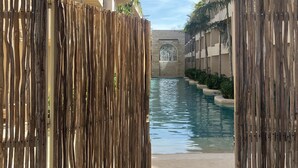 A wooden archway leading to a swimming pool area with a clear view of the pool and surrounding buildings. - Magic jungle apartment in Tulum (Tulum)