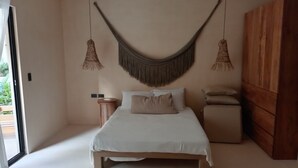 A bedroom with a bed, bedside tables, a wooden wardrobe, and a hanging macrame wall hanging. - Magic jungle apartment in Tulum (Tulum)