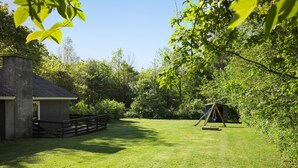 A grassy backyard with a wooden fence, a small shed, and a swing set. - Beautiful home in Toftlund with WiFi (Toftlund)