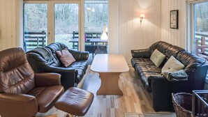 A cozy living room with leather sofas, a wooden coffee table, and large windows offering a view of the outdoors. - Beautiful home in Toftlund with WiFi (Toftlund)