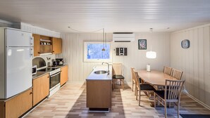 A compact kitchen with a central island, wooden cabinets, and a dining area with a table and chairs. - Beautiful home in Toftlund with WiFi (Toftlund)