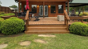 A wooden cabin with a deck, large windows, and a covered outdoor seating area. - #1 Top-Rated Waterfront Lodge on Lake Fork Pet Friendly (Alba)