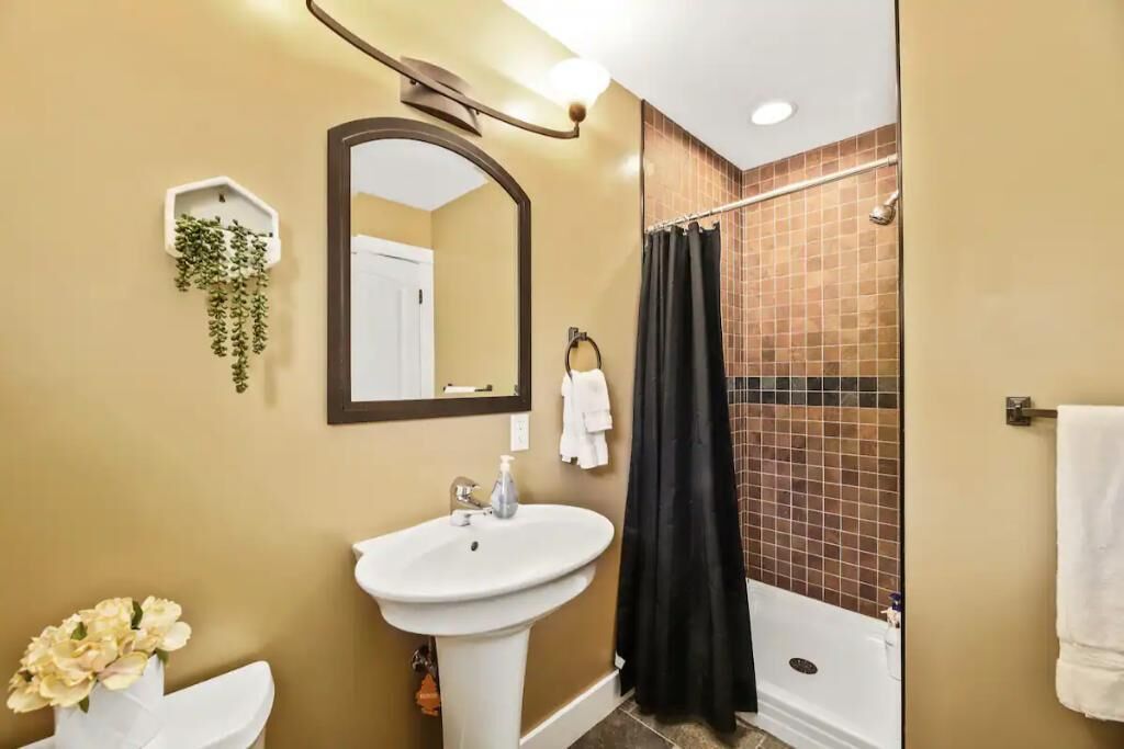 Un baño con lavamanos, espejo y ducha.