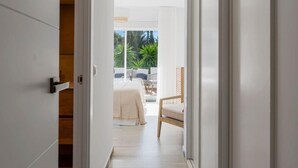 A modern hotel room with a large sliding glass door leading to a balcony with a bed and a chair.