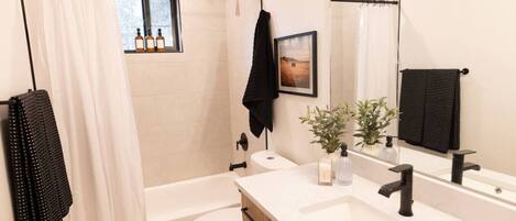 A modern bathroom with a bathtub, toilet, and vanity.