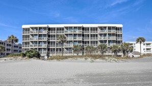 Een meerlaags hotel met balkons, nabij een strand.