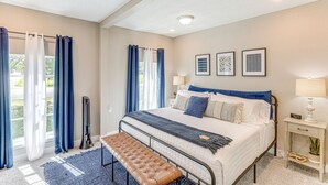 A bedroom with a bed, bench, bedside table, and curtains.