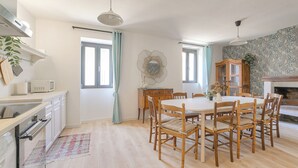 A spacious kitchen with a dining area, wooden cabinets, and a stone fireplace. - Gîte La Terrasse, near CNPE and Via Rhôna, ideal for cycling enthusiasts! (Lagnieu)