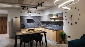A modern kitchen with a marble backsplash, wooden cabinets, and a built-in clock on the wall.