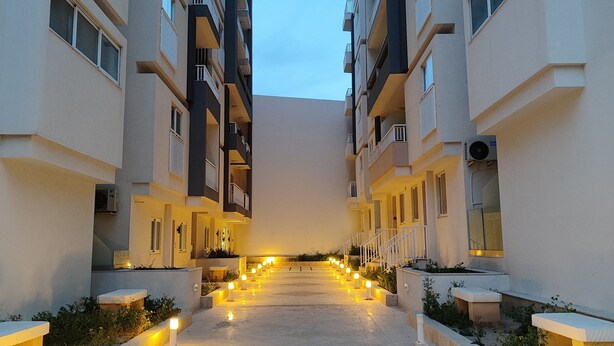A corridor in a modern apartment building with evenly spaced lights and a clear sky.